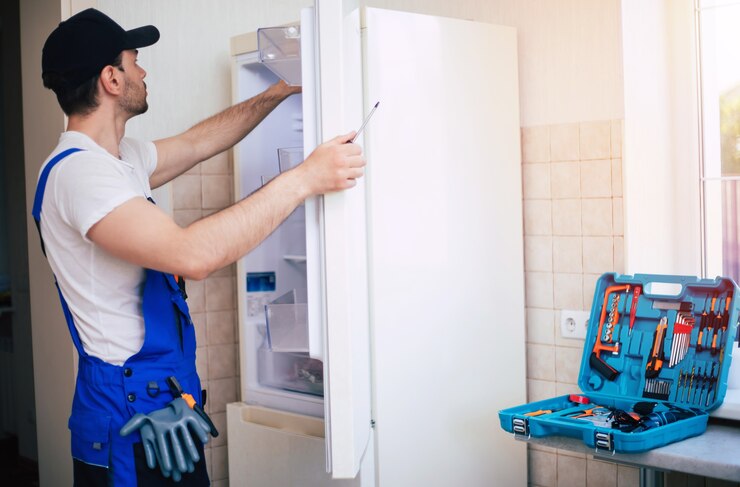 professional-young-repairman-worker-uniform-cap-with-modern-toolbox-with-equipment-is-repairing-refrigerator-kitchen_283617-2767